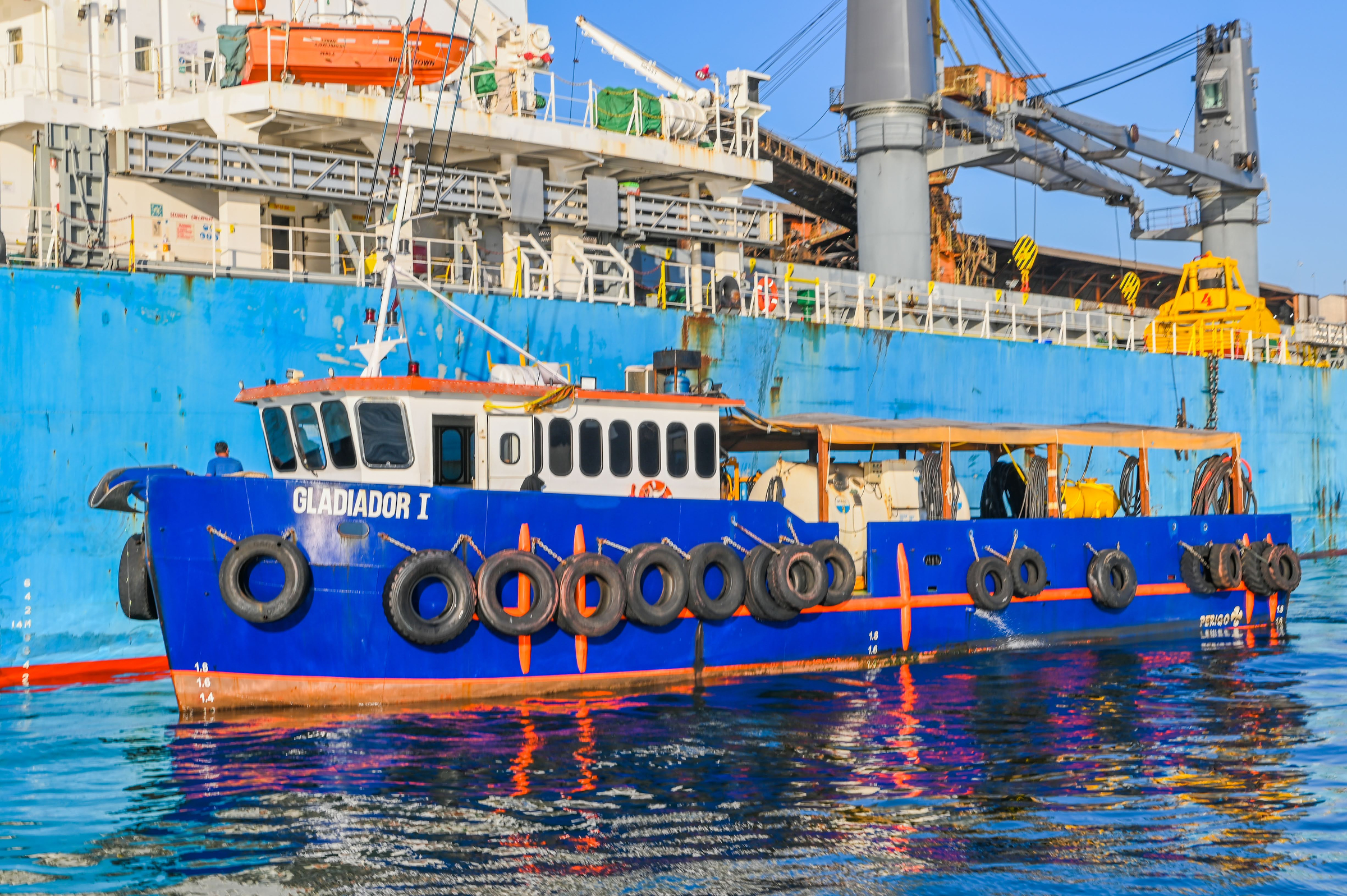 Embarcação Gladiador I atracada ao costado de um navio graneleiro